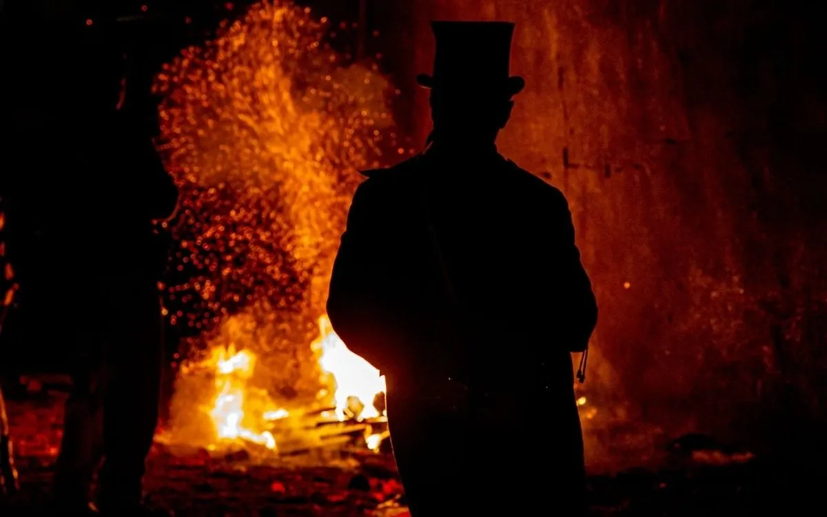 Een fakkeloptocht door een smalle straat in Lewes, met de brandende fakkels en de huizen dicht op elkaar.