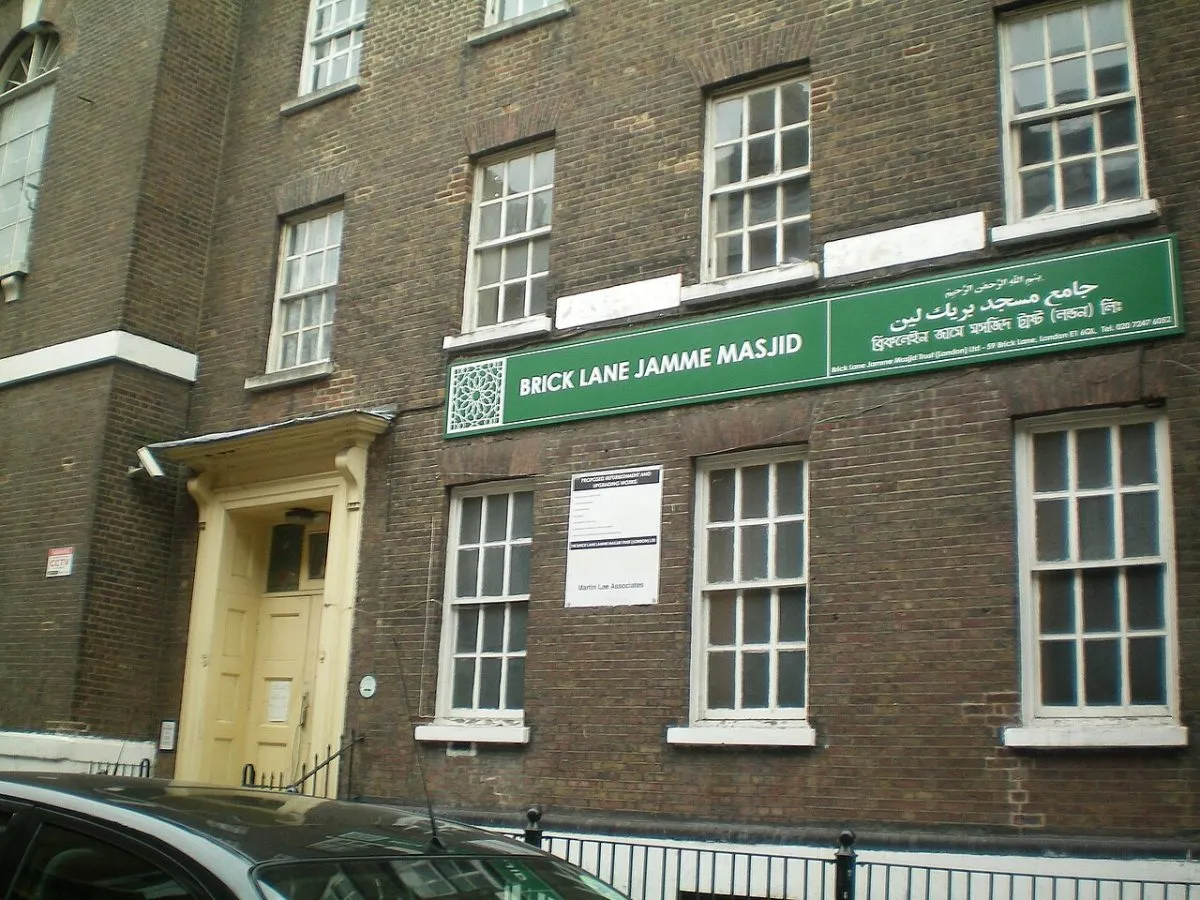 De gevel van Brick Lane Jamme Masjid op de hoek met Fournier Street, met de moderne minaret ernaast in beeld. Het contrast tussen het achttiende-eeuwse gebouw en de minaret is het onderwerp.