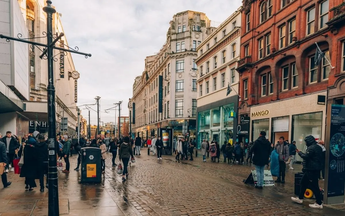 Een winkelstraat of high street op een feestdag, met open winkels en publiek. Praktisch beeld dat laat zien dat het leven doorgaat.