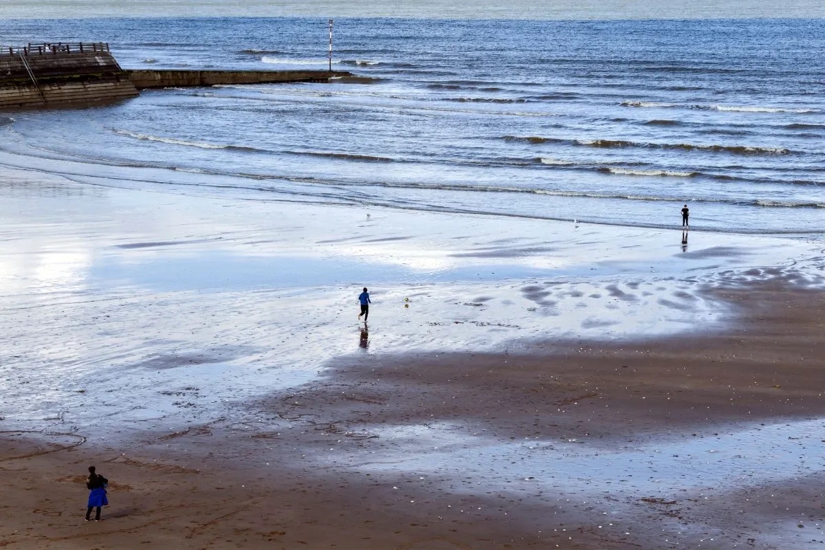 De pier van Brighton met het kiezelstrand ervoor, en mensen op de kiezels.
