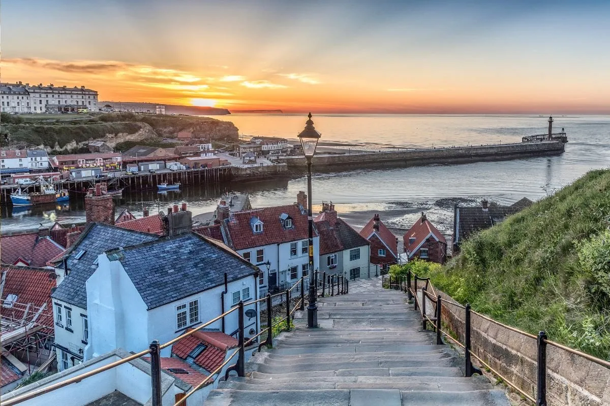 De haven van Whitby met de vissersboten en de gekleurde huizen tegen de helling.