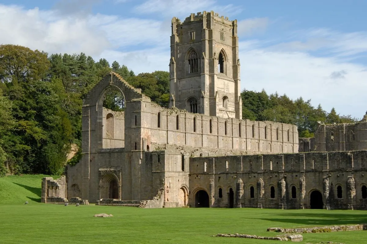 Fountains Abbey met de toren boven de ruïne, gezien vanaf de watertuinen van Studley Royal.