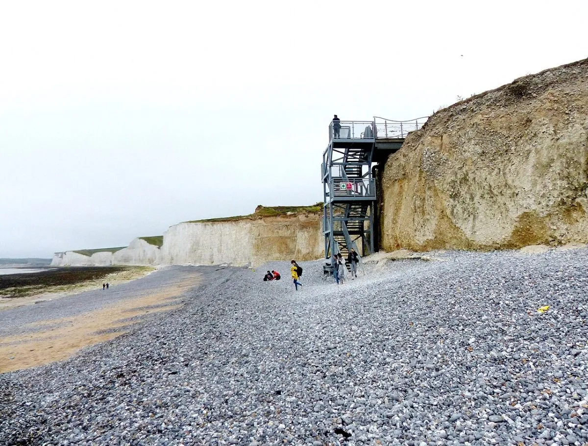 De metalen trap naar het strand bij Birling Gap, met het kiezelstrand en de kliffen eromheen. Het National Trust-gebouwtje mag in beeld.