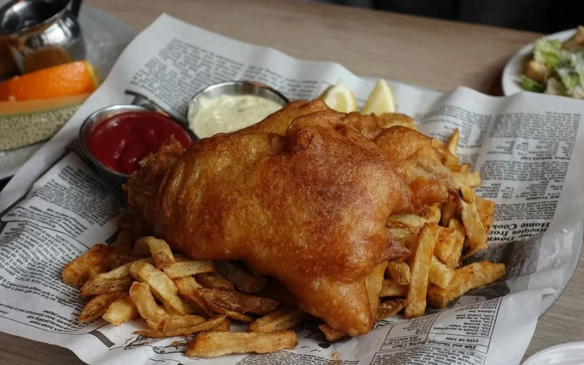 Het menubord van een Engelse fish-and-chipszaak met de prijzen leesbaar, van de straatkant gefotografeerd.
