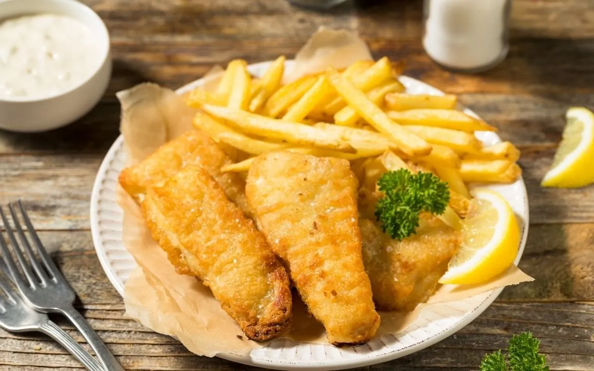 De toonbank van een chippy met de gefrituurde vis in de vitrine en de friteuse erachter.