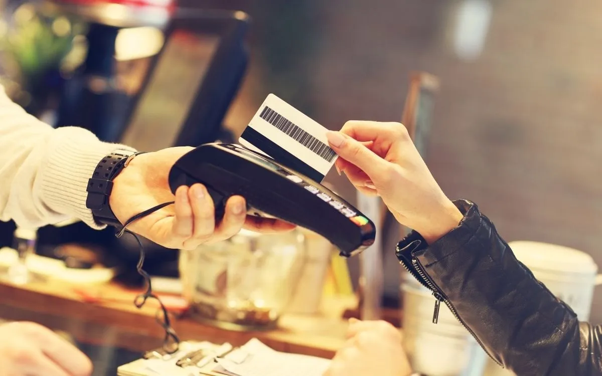 Een menukaart of bordje bij de ingang van een restaurant waarop staat dat er een discretionary service charge van 12,5% wordt toegevoegd.