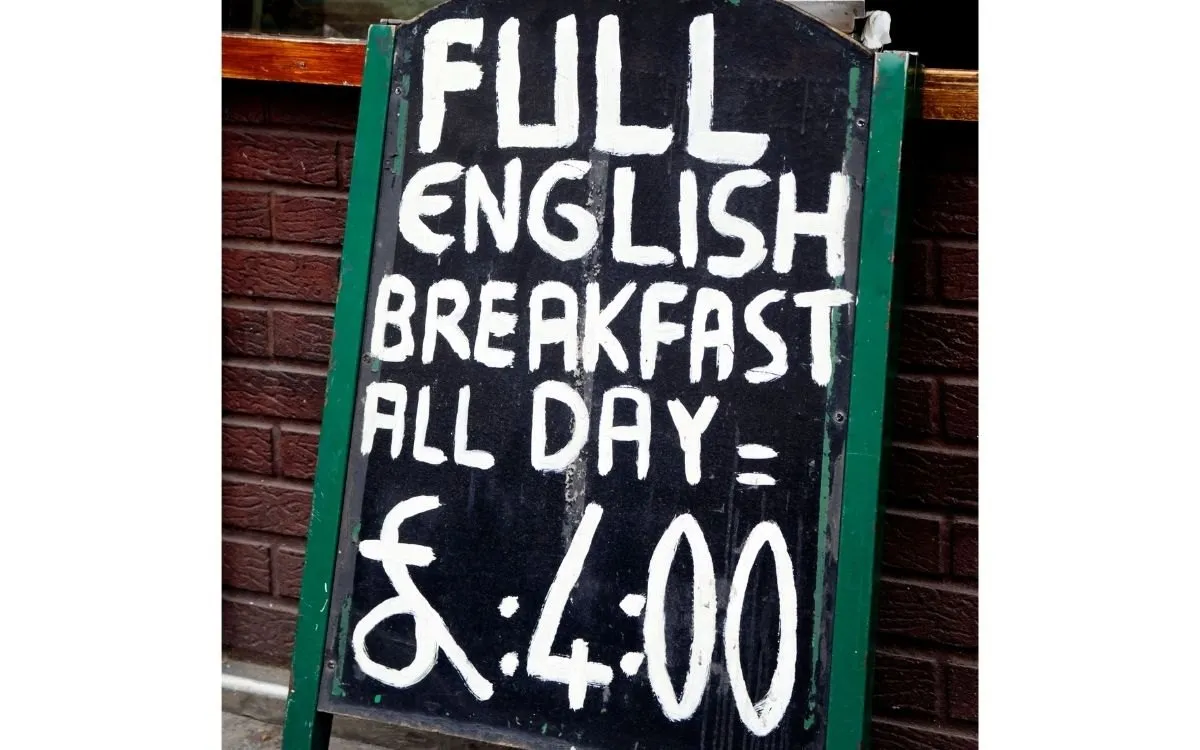 Een ontbijtbuffet of de toonbank van een café met een krijtbord of menukaart waarop de prijs van het ontbijt staat.