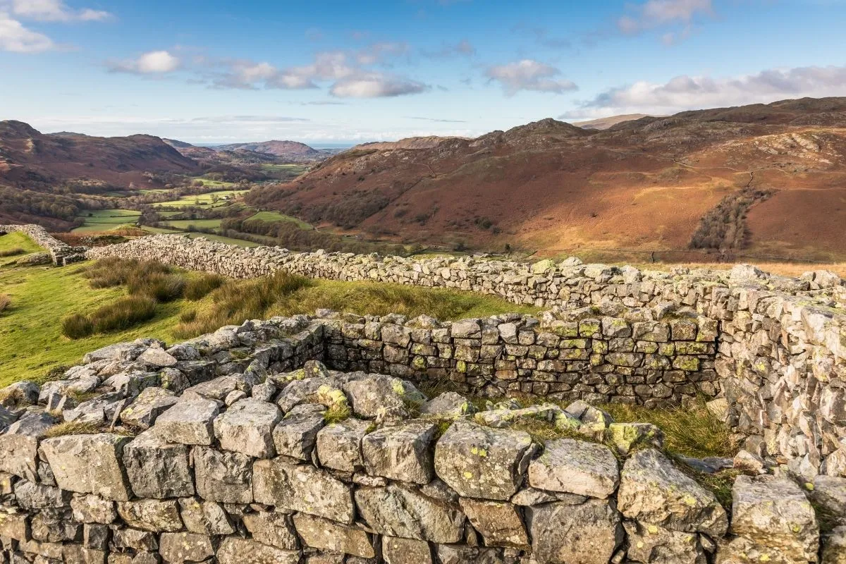 De resten van Hardknott Roman Fort op het plateau, met de vallei van Eskdale erachter. Van een afstand, zodat de ligging duidelijk wordt.