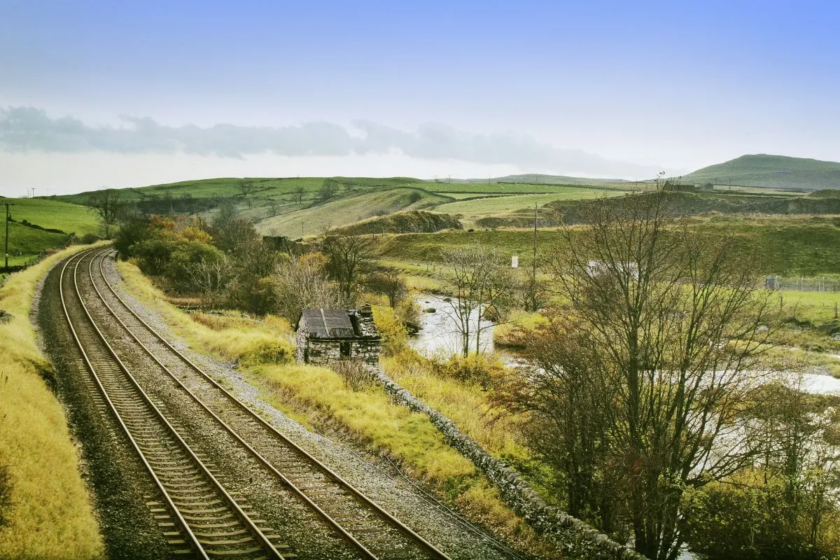 Een perron van een museumstation met vrijwilligers in ouderwets uniform, borden en koffers. Goathland, Sheffield Park of Toddington werken hier goed.