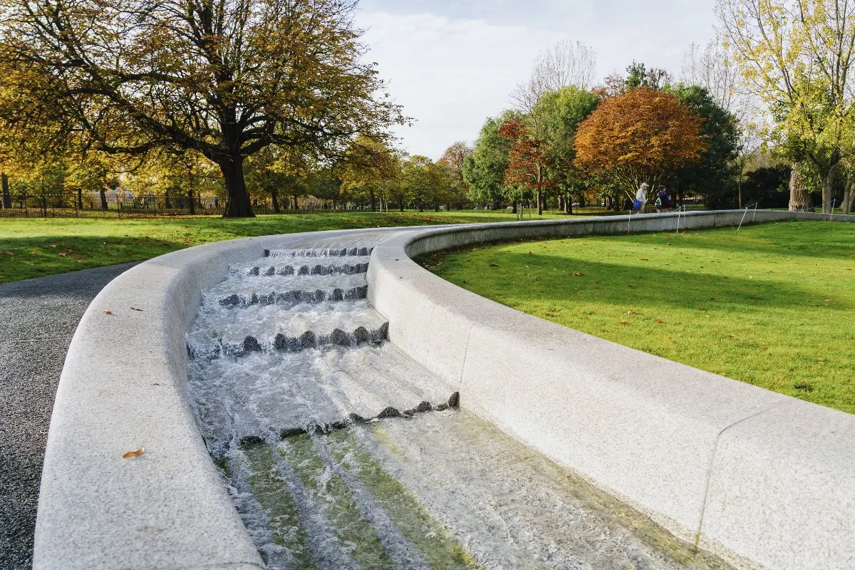 Het pad langs West Carriage Drive of de brug over de Serpentine, waar de grens tussen de twee parken loopt. Of een breed beeld van het park met de skyline erachter.
