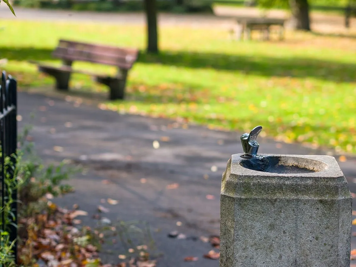 Een openbare drinkwaterfontein in Engeland, bijvoorbeeld een van de blauwe fonteinen in Londense parken, met iemand die een fles vult.