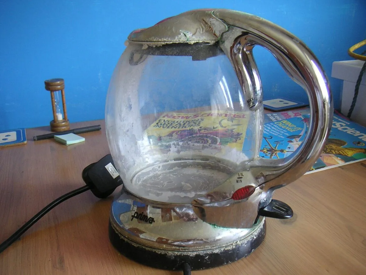 De binnenkant van een waterkoker met witte kalkaanslag, of een glas water met kalkstrepen, in een Engels hotel of B&B. Van dichtbij, zodat de aanslag goed te zien is.