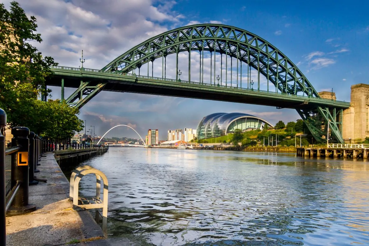 De Gateshead Millennium Bridge tijdens het kantelen, met de boog schuin omhoog en toeschouwers op de kade.