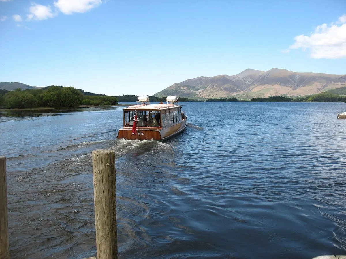 Derwentwater vanaf de oever bij Keswick, met de boot op het meer en de heuvels erachter.