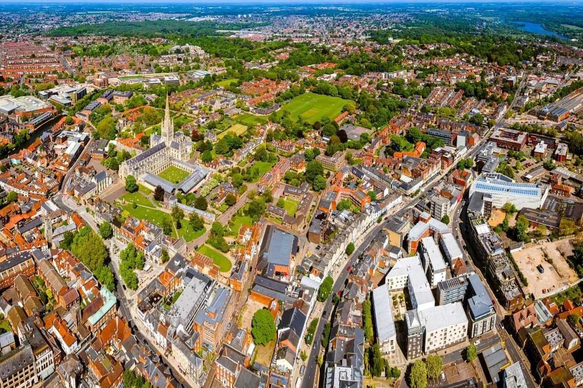 De kathedraal van Norwich vanaf het kloosterhof, met de spits boven de gang uit, zodat de hoogte zichtbaar is.