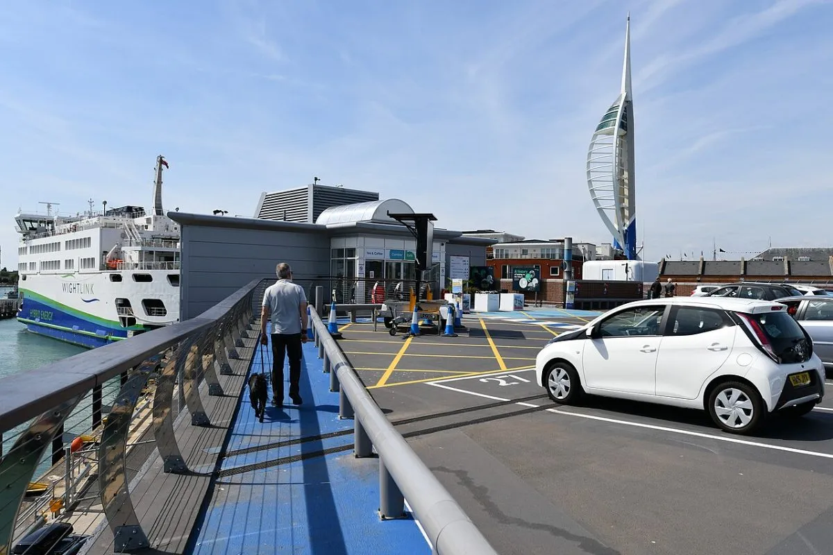 Een autoveerboot van Wightlink of Red Funnel die de haven binnenvaart, met auto's op het dek zichtbaar. Het gaat om de schaal van een autoveer tegenover een sneldienst.