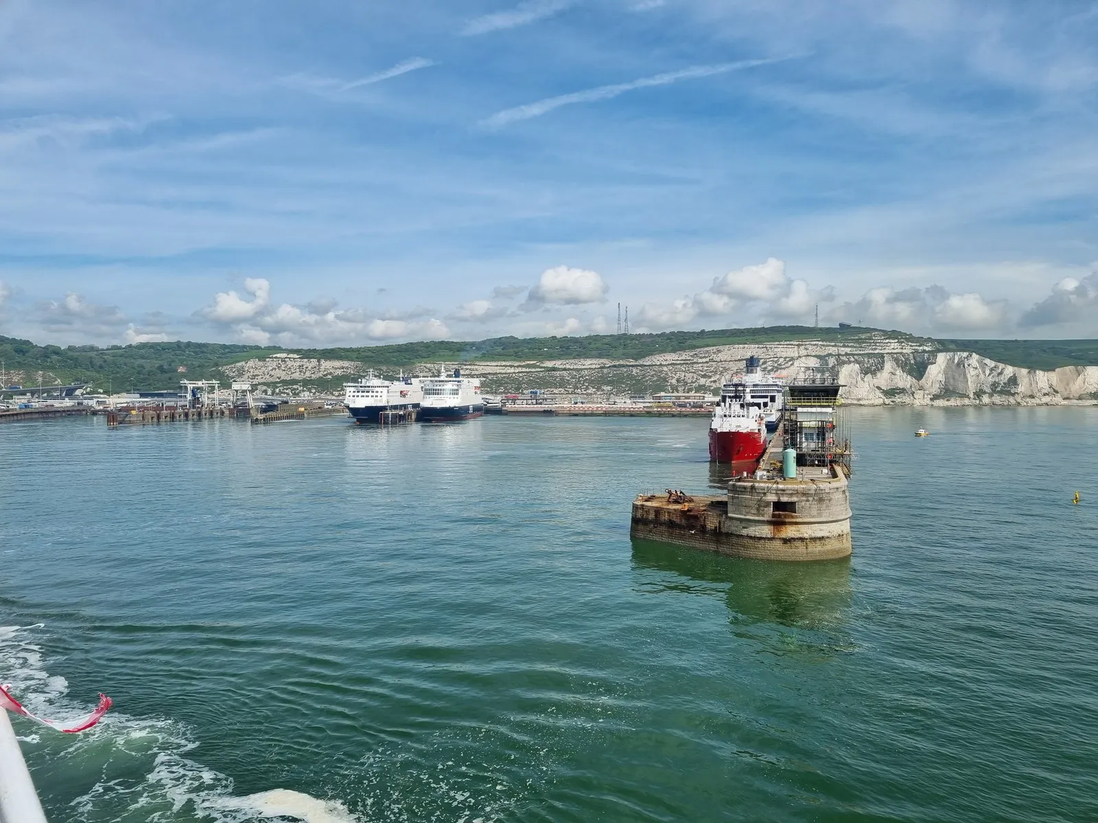 De witte kliffen van Dover vanaf het pad bij het bezoekerscentrum van het National Trust, met de haven en een veerboot in beeld.