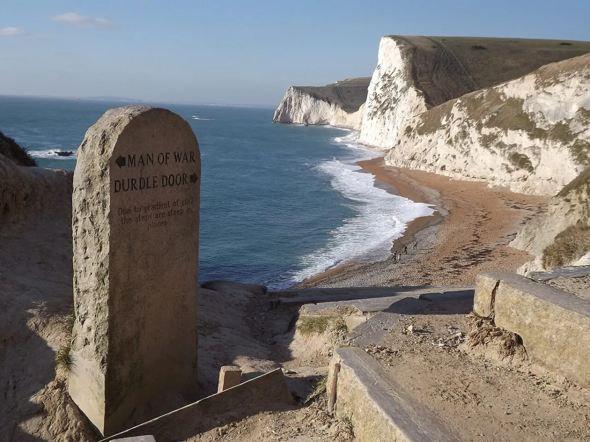 Durdle Door, de rotsboog in zee bij Lulworth, van bovenaf vanaf het kustpad, met het strand ernaast.