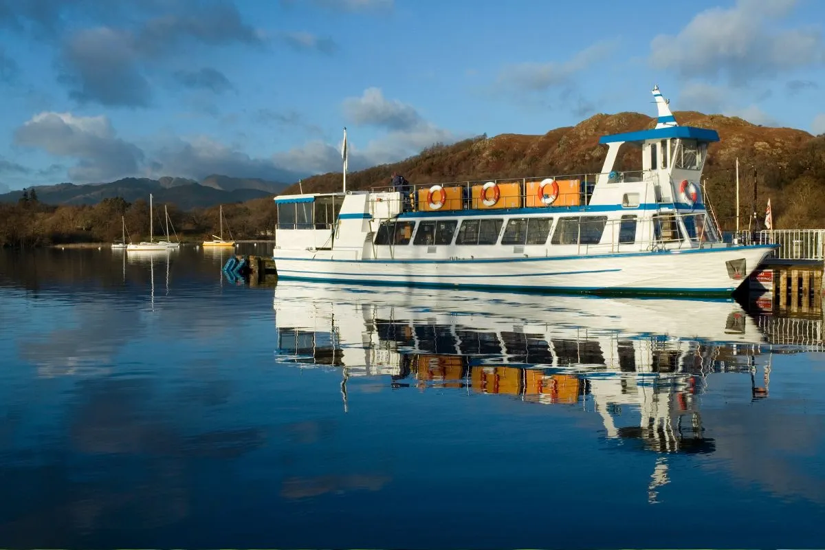 De open dubbeldekker van lijn 599 onderweg tussen Bowness en Grasmere, of een boot van Windermere Lake Cruises aan de steiger.