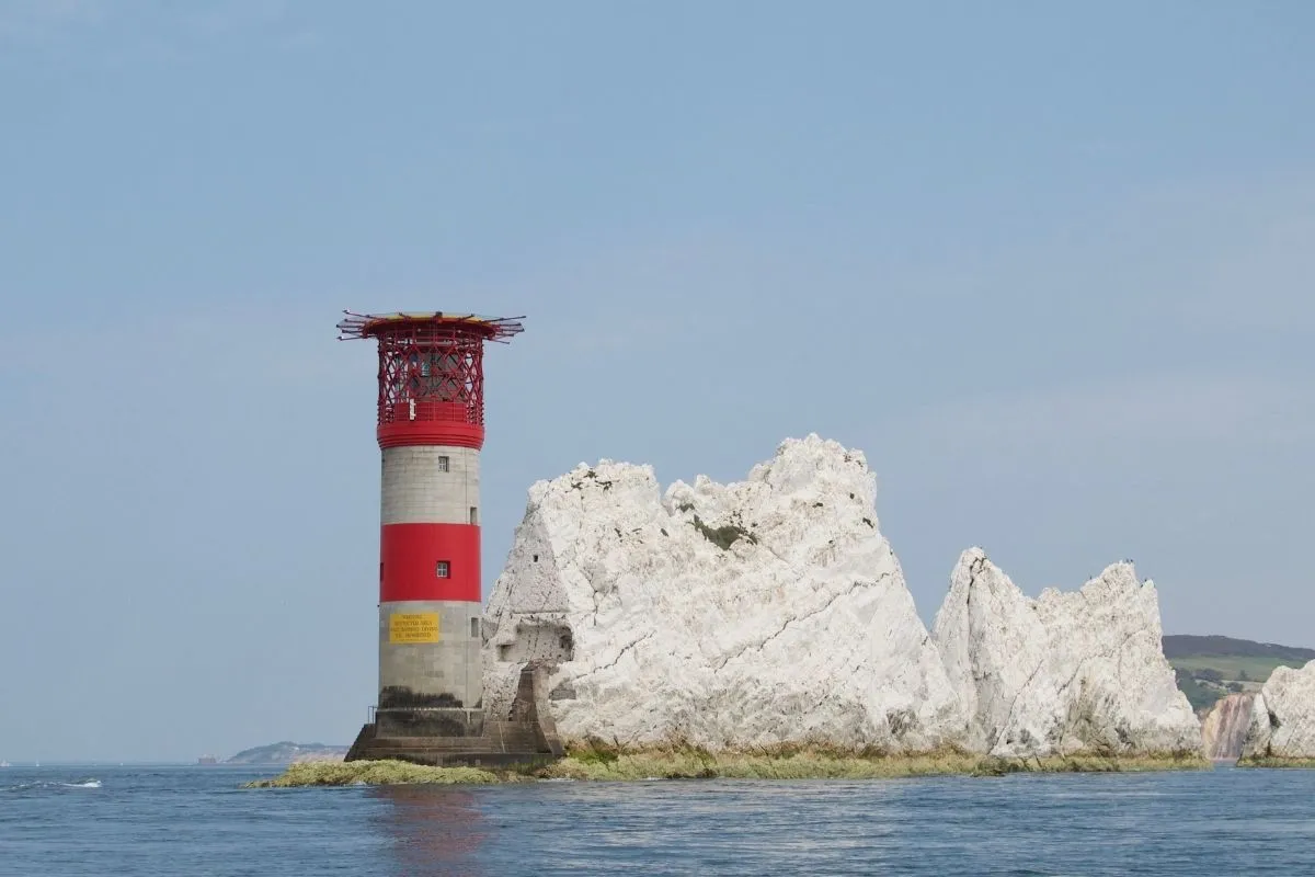 De vuurtoren van The Needles van dichtbij vanaf zee, met de granieten toren en de rotsen eromheen.