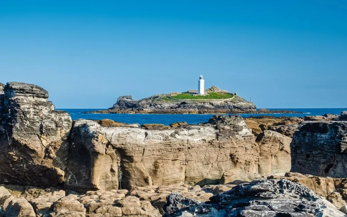De rood-wit gestreepte vuurtoren van Beachy Head onder de krijtklif, gezien vanaf het klifpad erboven.