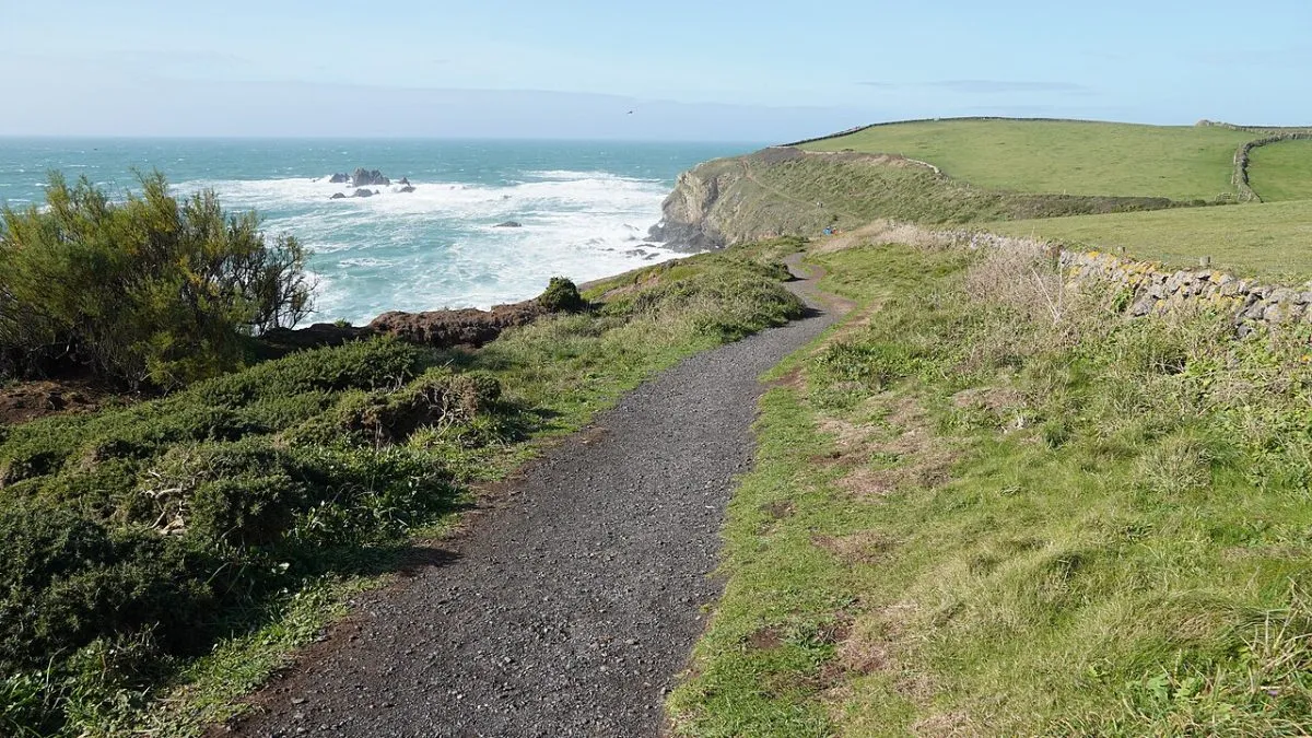 Het kustpad tussen Lizard Point en Kynance Cove, met het pad in beeld en de serpentijnrotsen en de zee eronder. Liefst een stuk waar de route zichtbaar doorloopt.